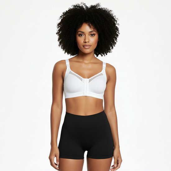 Vrouw met krullend haar, draagt een witte sportbeha met rits aan de voorkant en zwarte short.