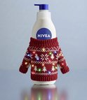 NIVEA bodylotion fles in een rood gebreide kersttrui met lichtjes.