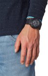 Man met spijkerbroek en donkerblauwe trui draagt een zwarte G-Shock horloge om zijn linkerpols.