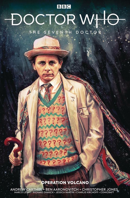 De Zevende Doctor in een beige jas, vest met vraagtekens, stropdas en hoed, met een paraplu.