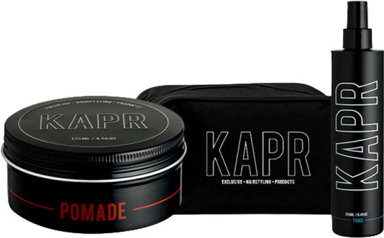 Zwart blikje KAPR Pomade, een zwarte toilettas en een zwarte fles KAPR Tonic op een witte achtergrond.