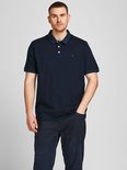Man in donkerblauw poloshirt met wit geborduurde "&" op borst, navy kraag, drie witte knopen.