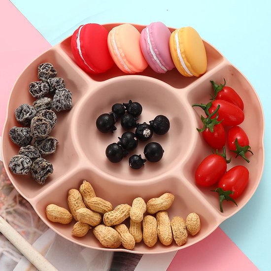 Roze snackbord met macrons, gedroogde pruimen, bessen, kerstomaatjes en pinda's.