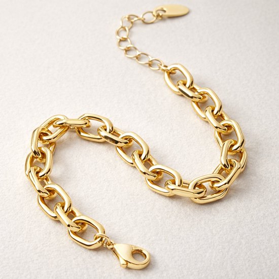 Gouden schakelarmband met grove schakels, geplaatst op een lichte ondergrond.