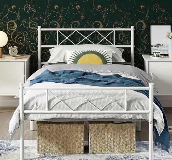 Wit metalen bedframe met diamantpatroon hoofdbord en voetbord, gestileerde groene achtergrond met gouden krullen.