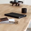 Zwarte, gesloten tablet case op een houten tafel. Naast een portemonnee, schaar en potje.