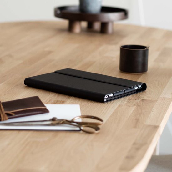 Zwarte, gesloten tablet case op een houten tafel. Naast een portemonnee, schaar en potje.