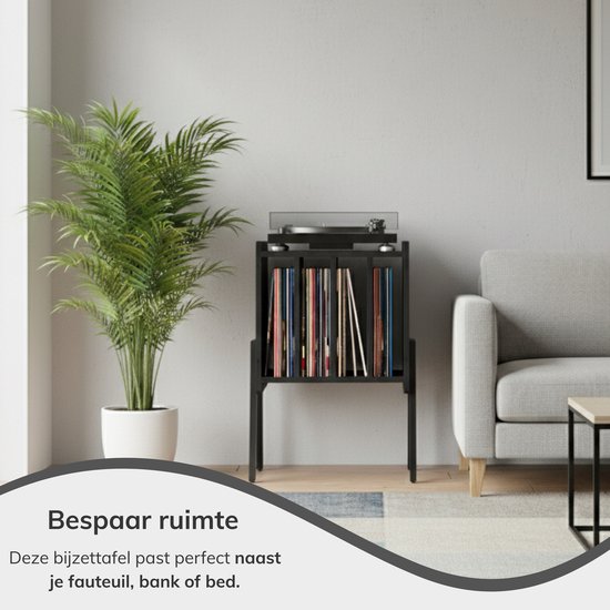 Zwart vinyl opbergsysteem met platenspeler, naast een bank en plant in een woonkamer.