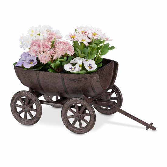 Bruin metalen wagentje gevuld met diverse bloemen, staand op kiezelstenen.