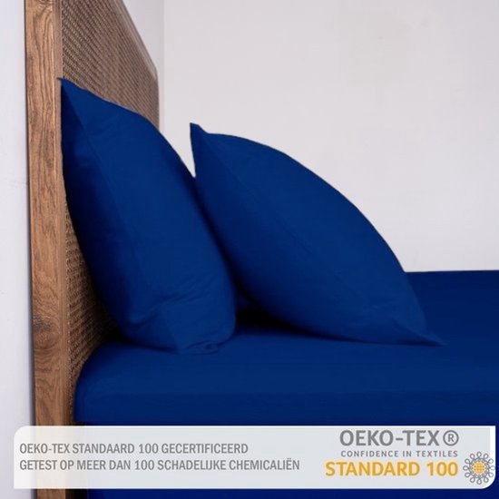 Donkerblauwe lakens en kussenslopen op een bed met houten hoofdeinde, met OEKO-TEX certificaat.