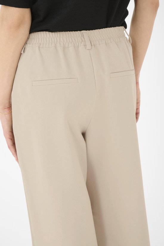 Detail van de achterkant van een beige broek, met elastische taille en twee paspelzakken.