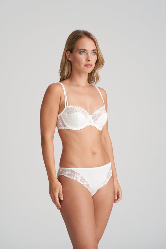 Model draagt een witte balconnetbeha met kanten bloemenmotief en bijpassend broekje, naar de zijkant kijkend.
