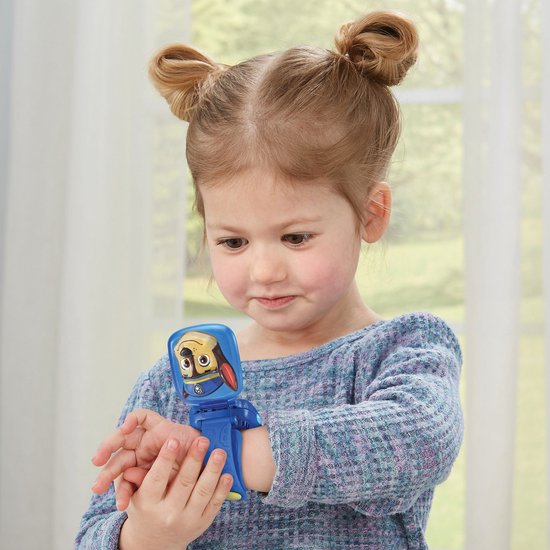 Een jong meisje met staartjes draagt een blauw Paw Patrol horloge dat opengeklapt is. Chase kijkt vanaf het scherm.
