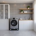 Zilveren wasmachine op zwarte verhoger in een moderne wasruimte.
