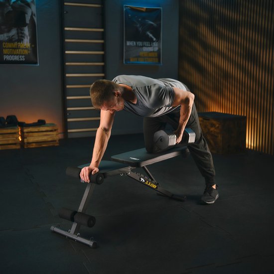 Man in grijs shirt traint op een zwarte fitnessbank met een verstelbare dumbbell.