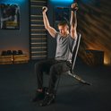 Man in grijs shirt traint met een zwarte fitnessbank en weerstandsbanden.