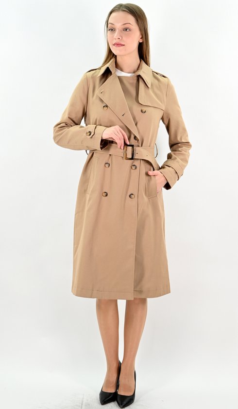 Model in camelkleurige lange trenchcoat, met ceintuur en knopen, hand in de zak.