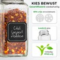 Glazen kruidenpotje gevuld met chilivlokken. Zwart etiket met handgeschreven tekst "Chili (peper) vlokken".
