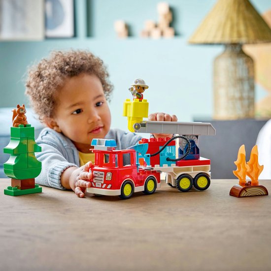 Enfant jouant avec un camion de pompiers, une échelle, un arbre, un écureuil et un pompier.