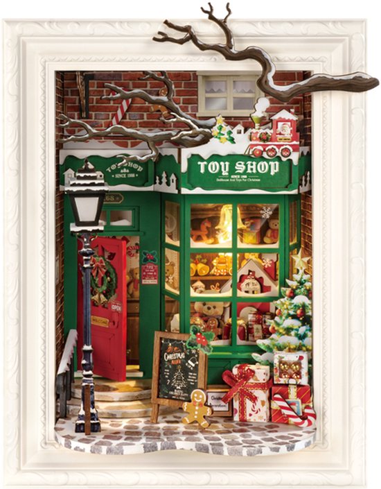 Een gedetailleerd miniatuur kerstwinkel poppenhuis in een witte lijst, met rode deur, kerstboom en speelgoed.