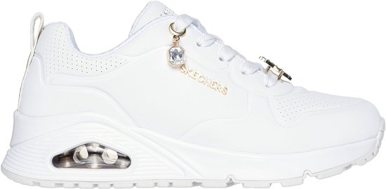 Sneaker Skechers blanche avec logo doré Skechers, breloque bijou et un passant d'œillet étoilé.