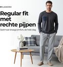 Man in grijze joggingbroek met rechte pijpen, trekkoord en zwarte bies.