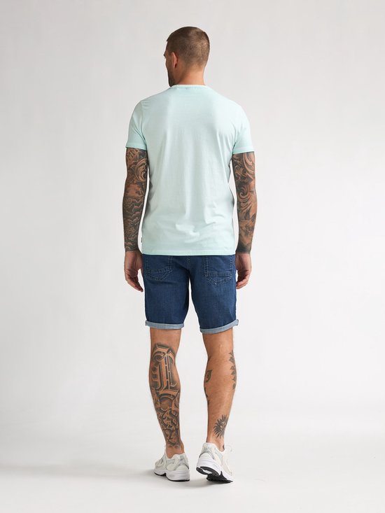 Man van achteren in lichtgroen T-shirt en spijkerbroek.