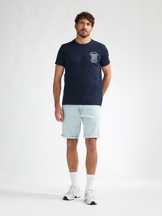 Man in donkerblauw T-shirt en lichte spijkerbroek.