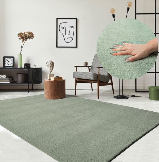 Un salon à la décoration moderne avec un tapis vert clair, un fauteuil à motif graphique et un gros plan d'une main sentant la texture douce du tapis.