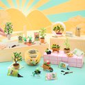 Miniatuur tuin scène met verschillende plantjes in potjes, een kruiwagen, gieter en zakjes potgrond.