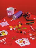 Kleurrijke snoepjes, dobbelstenen, een gamepad, een skateboard, kaarten en een mok met 'HUG ME MUG'.