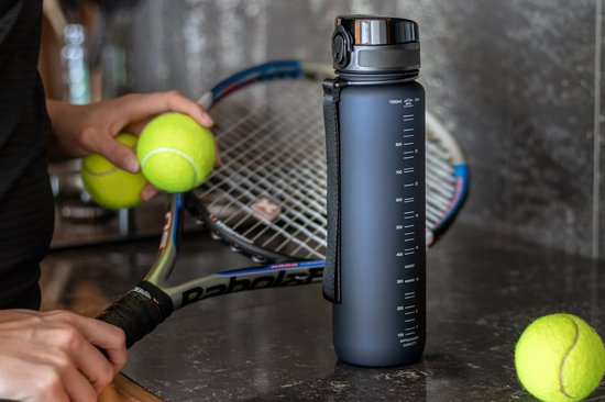 Donkerblauwe King Mungo drinkfles met volumeaanduiding, naast tennisrackets en ballen.