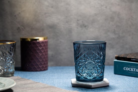 Blauw glas met geometrisch patroon, naast een paarse en zilveren kan.