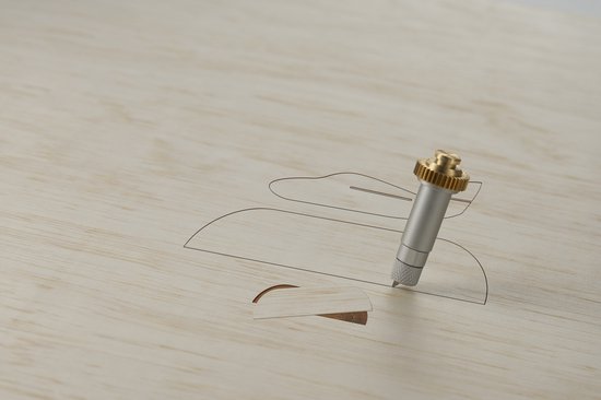 Cricut mes snijdt rond een ontwerp in licht hout.