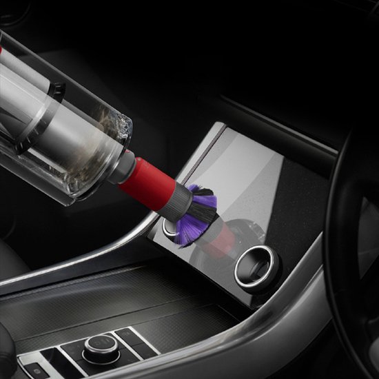 Rood en grijs hulpstuk met paars-zwarte borstelharen, dat auto-interieur schoonzuigt.