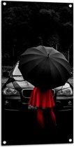 WallClassics - Tuinposter – Vrouw in Rood bij Zwarte Auto met Paraplu - 50x100 cm Foto op Tuinposter (wanddecoratie voor buiten en binnen)