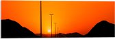 WallClassics - Acrylglas - Zonsondergang over Weg met Lantaarnpalen tussen Bergen - 90x30 cm Foto op Acrylglas (Wanddecoratie op Acrylaat)