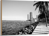 Hout - Palmbomen op het Strand met Uitzicht op Hoge Gebouwen Zwart/Wit - 100x75 cm - 9 mm dik - Foto op Hout (Met Ophangsysteem)