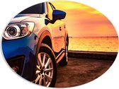 PVC Schuimplaat Ovaal - Luxe Blauw Gekleurde Geparkeerde Auto tijdens Zonsondergang - 68x51 cm Foto op Ovaal (Met Ophangsysteem)