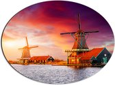Dibond Ovaal - Nederlandse Windmolens aan het Water onder Paars met Oranje Lucht - 56x42 cm Foto op Ovaal (Met Ophangsysteem)