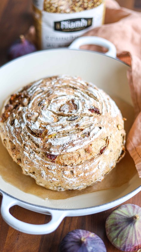 Goudbruin, rond brood met een gestoomde bovenkant, bestrooid met bloem, in een gietijzeren pan.