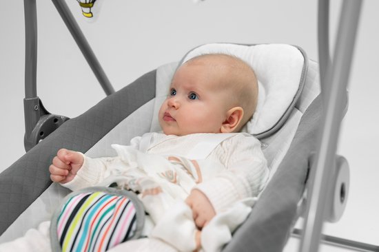 Een baby met blauwe ogen ligt in een schommelstoel.