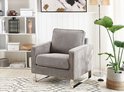 Lichtgrijze corduroy fauteuil in een modern interieur met open kast en plant.