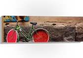 WallClassics - Hout - Geparkeerde Fiets bij Muur met Watermeloen Wielen - 90x30 cm - 9 mm dik - Foto op Hout (Met Ophangsysteem)