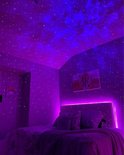 Een slaapkamer verlicht met een paarse sterrenhemel projectie en ledstrips. Een bed met kussens en een wandkleed met zon en maan motief.