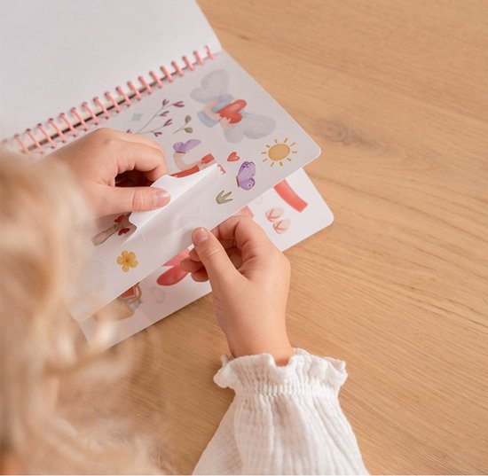 Kind pakt stickers met vlinders, bloemen, een egel en een zon uit een schetsboek.