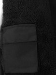Detail van de zwarte teddybinnenvoering en een opgestikte zak op een softshell jas.