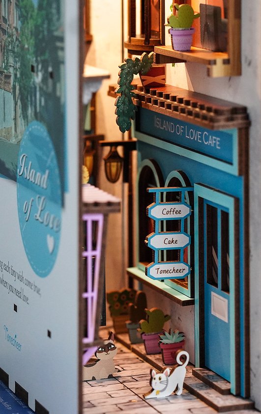 Close-up van de miniatuur 'Island of Love' café-gevel, met een winkelbord en katten.