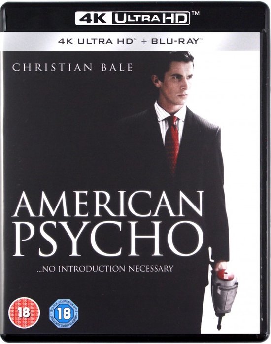 Christian Bale draagt een donker pak met rode stropdas in "American Psycho".