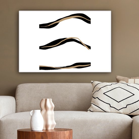 Abstract schilderij met drie zwarte en goudkleurige lijnen boven een beige bank met kussens.